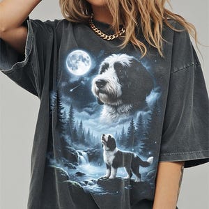 May include: Dark gray t-shirt featuring a detailed graphic of a dog under a full moon. The design includes a waterfall, forest, and a second dog image. The shirt has a vintage, worn look.