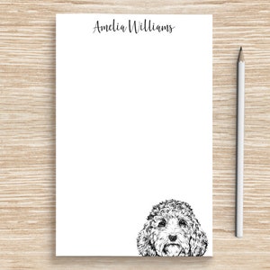 May include: White notepad with the name "Amelia Williams" printed at the top. A black and white illustration of a dog's head is at the bottom of the notepad.