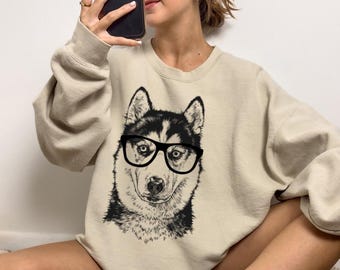 May include: A beige sweatshirt with a black and white illustration of a husky wearing glasses.