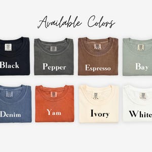 Puede incluir: Una selecci&oacute;n de camisetas dobladas en varios colores, incluyendo negro, pimienta, espresso, bah&iacute;a, mezclilla, &ntilde;ame, marfil y blanco. El texto "Available Colors" est&aacute; escrito en cursiva en la parte superior de la imagen.