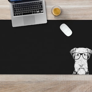 May include: Black desk mat with a white illustration of a dog wearing glasses. The dog is looking directly at the viewer.