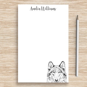May include: White notepad with the name "Amelia Williams" printed at the top. A black and white illustration of a wolf's face is at the bottom of the notepad.