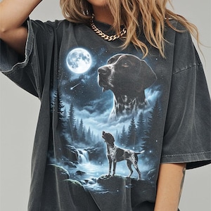 May include: Dark grey t-shirt with a detailed graphic of a dog under a full moon in a forest scene. The design includes a waterfall, trees, and a starry sky. The shirt has a vintage, worn appearance.