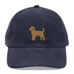 May include: A navy blue corduroy baseball cap with an embroidered golden brown dog silhouette.