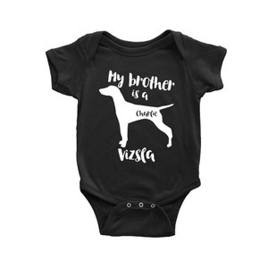 Puede incluir: Mono negro para bebé con texto blanco que dice "Mi hermano es un Charlie Vizsla". El mono presenta una silueta blanca de un perro Vizsla.