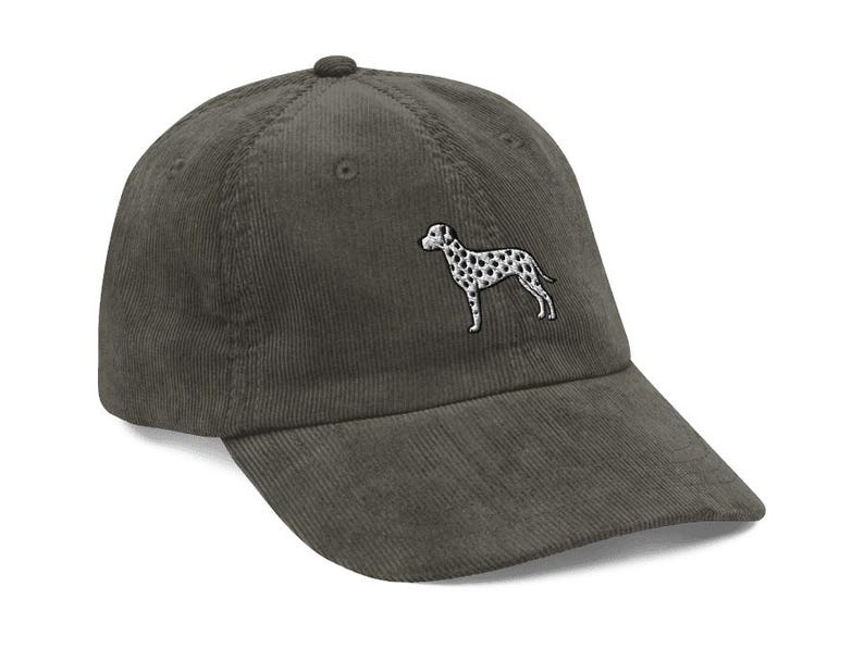 May include: A dark green corduroy baseball cap with an embroidered white and black Dalmatian dog on the front.