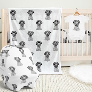 May include: A white baby blanket, car seat cover, and onesie with a black and white illustration of a dog's head repeated in a pattern.