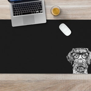 May include: Black desk mat with a white illustration of a dog wearing glasses. The dog is looking directly at the viewer.