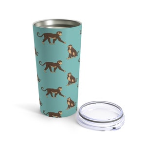 May include: A stainless steel tumbler with a teal blue background and a repeating pattern of brown monkeys. The tumbler has a clear lid.