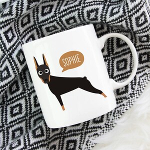 May include: White ceramic mug with a black and brown Doberman Pinscher illustration and the name "Sophie" in a speech bubble.