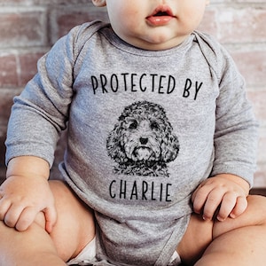 May include: A gray long-sleeve bodysuit with the text "PROTECTED BY" and a black and white illustration of a dog with the name "CHARLIE" underneath.