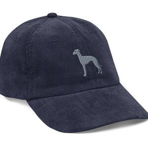 May include: A navy blue corduroy baseball cap with an embroidered grey silhouette of a dog on the front.