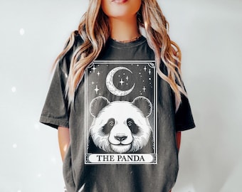 May include: A grey t-shirt featuring a black and white illustration of a panda bear with a crescent moon and stars. The text "THE PANDA" is printed below the illustration.