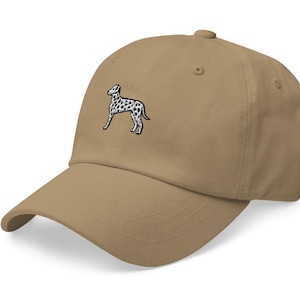 May include: A tan baseball cap with an embroidered black and white dalmatian dog on the front.