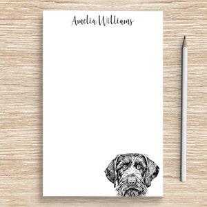 May include: White notepad with the name "Amelia Williams" printed at the top. A black and white illustration of a German Shorthaired Pointer dog's head is at the bottom of the notepad.