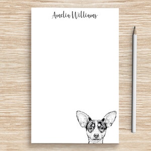 May include: White notepad with the name "Amelia Williams" printed at the top. A black and white illustration of a dog's head is at the bottom of the notepad.