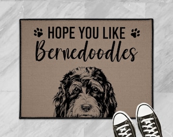 May include: A brown doormat with the text "HOPE YOU LIKE BERNEDoodles" and a black and white illustration of a Bernedoodle dog.