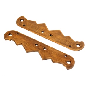 May include: Two wooden decorative brackets with a zigzag design and a warm brown finish. Each bracket has multiple pre-drilled holes and rounded ends. The brackets are designed to be mounted on a surface.