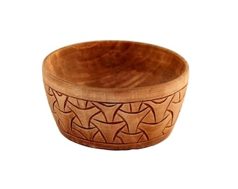 May include: A wooden bowl with a carved geometric pattern. The bowl is light brown and has a smooth, rounded shape.