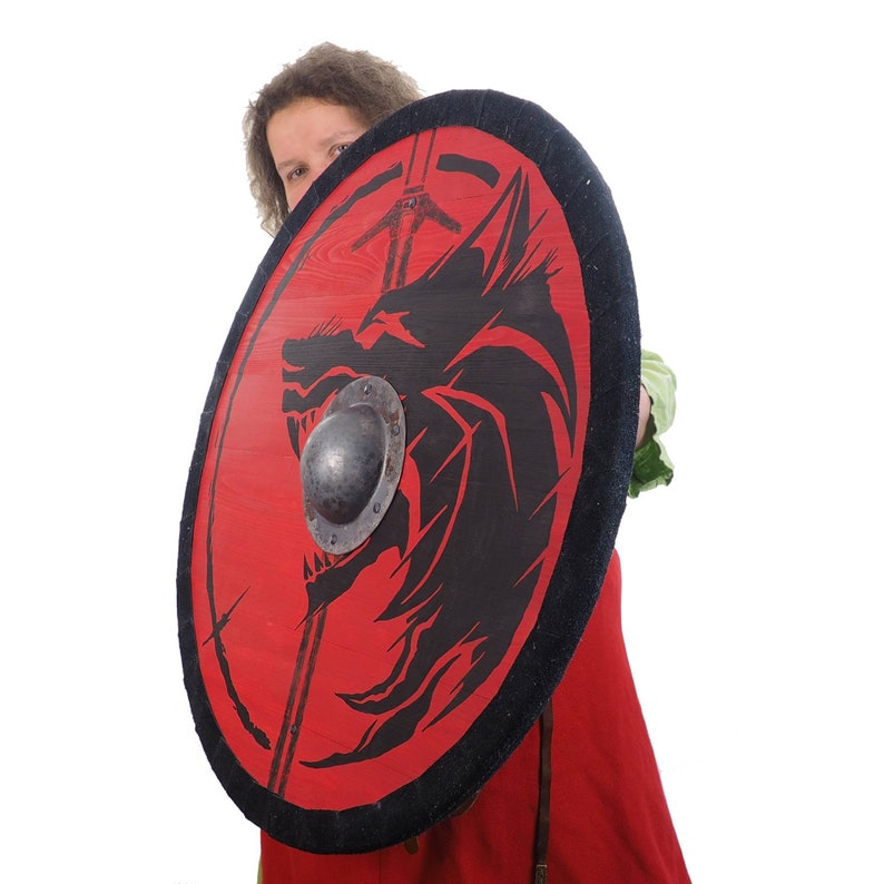 May include: A red and black shield with a wolf design. The shield has a black leather trim and a metal boss in the center.