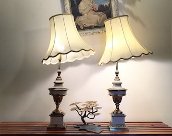 Może przedstawiać: Dwie białe lampy stołowe ze złotymi akcentami i białymi kloszami. Lampy stoją na drewnianej powierzchni z małym drzewem bonsai przed nimi.