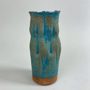 May include: A blue and brown ceramic vase with a textured surface and a slightly uneven rim.