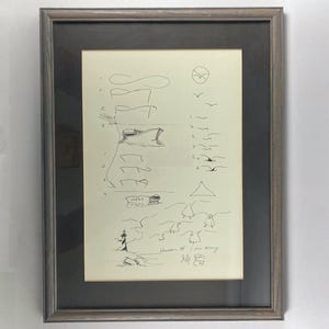 May include: A framed black and white drawing of a lighthouse, a boat, and birds. The drawing is on a cream-colored paper with the text "Location # 1 on Mary's World" and "July 88" written at the bottom.