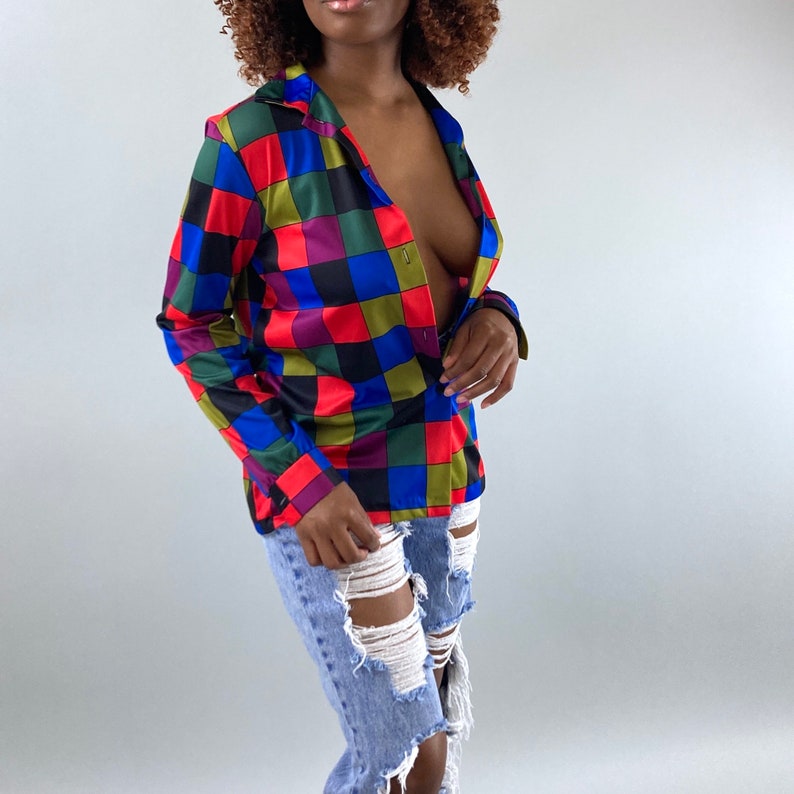 May include: A colorful checkered button-down shirt with a blue, red, green, and black pattern. The shirt is made of a silky material and has a relaxed fit.
