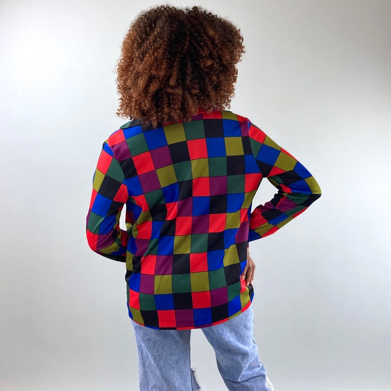 May include: A long-sleeved shirt with a checkered pattern in shades of red, blue, green, black, and purple.