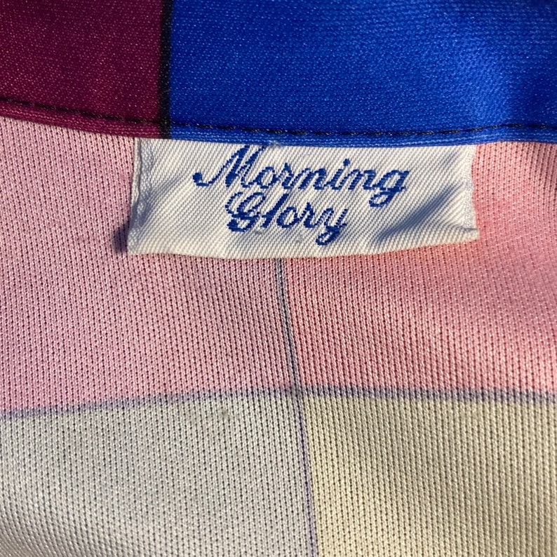 May include: A white label with the text "Morning Glory" written in blue cursive script on a pink and white checkered fabric.