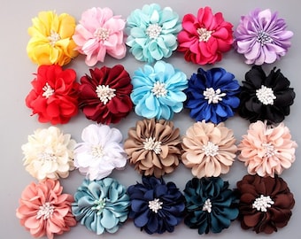 May include: Twenty-four assorted fabric flower hair clips in various colors, including pink, blue, red, yellow, brown, and white. Each flower has a pearl-like center.