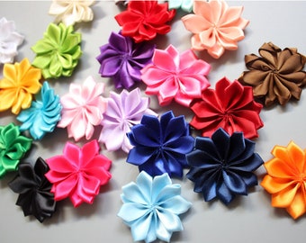 May include: A collection of colorful satin flower embellishments in various shades, including white, red, pink, purple, blue, green, and orange. These decorative flowers are arranged on a gray surface, showcasing their detailed petal design. Ideal for crafting and embellishing projects.