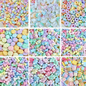 Puede incluir: Nueve conjuntos diferentes de encantos de resina de color pastel, cada conjunto con un diseño diferente. Los diseños incluyen conos de helado, estrellas, donas, alas, corazones, huesos y más.