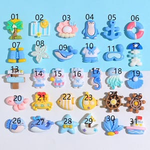 May include: A collection of miniature resin ocean-themed charms in various shapes and colors. Includes a tree, sun, flower, penguin, anchor, life preserver, binoculars, starfish, whale, sailor shirt, goggles, jellyfish, and more.