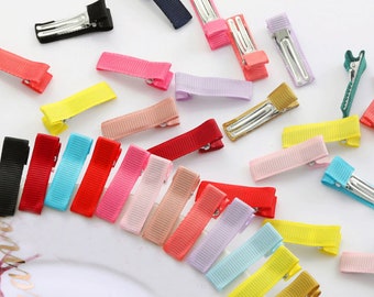 May include: Assortment of colorful ribbon hair clips. The clips are made of metal with a ribbon attached. The ribbons are in various colors, including red, blue, yellow, green, pink, and purple.