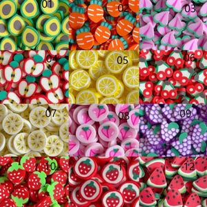 May include: A collection of colorful polymer clay fruit and vegetable slices. The image includes avocado, carrots, pink flowers, apples, lemons, cherries, bananas, pink heart-shaped fruits, grapes, strawberries, strawberry circles, and watermelon slices.