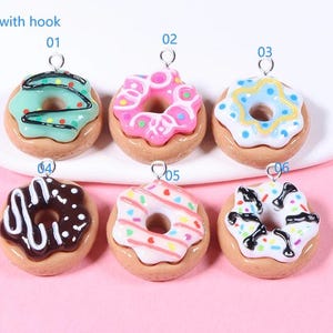 May include: Six colourful donut charms with a hook for hanging. The donuts are decorated with sprinkles, chocolate and frosting. The charms are numbered 01 through 06.