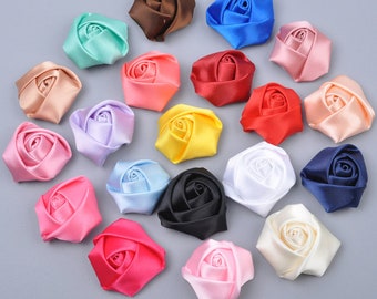 May include: Assortment of 20 satin fabric rose flower embellishments in various colors, including pink, blue, red, yellow, white, black, brown, and cream.
