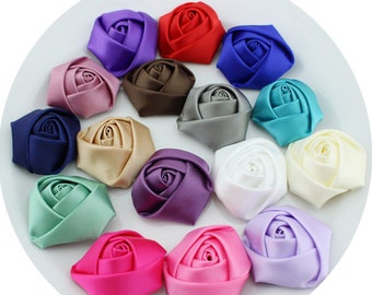 May include: Assortment of 15 satin fabric rose flower embellishments in various colors, including purple, red, brown, gray, teal, white, beige, green, pink, and lavender.