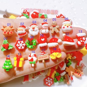 May include: Assortment of Christmas themed resin cabochons in various colors and designs, including a snowman, Santa Claus, reindeer, a Christmas tree, a snowflake, a wreath, a candy cane, a bell, and a stocking.
