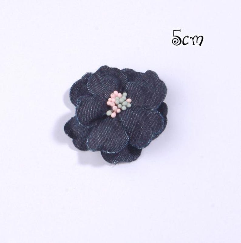 Puede incluir: Una flor de mezclilla azul oscuro con un centro rosa y verde, que mide 5 cm. La flor tiene m&uacute;ltiples p&eacute;talos y est&aacute; sobre un fondo blanco. El texto "5cm" es visible en la imagen.
