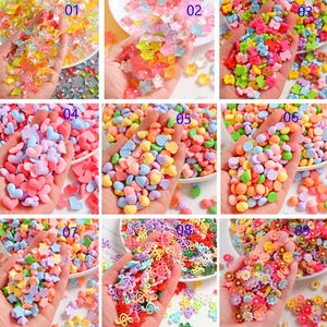 Puede incluir: Nueve recipientes diferentes de chispas de colores, cada uno con una forma diferente. Las chispas tienen forma de estrellas, corazones, círculos, notas musicales y flores.