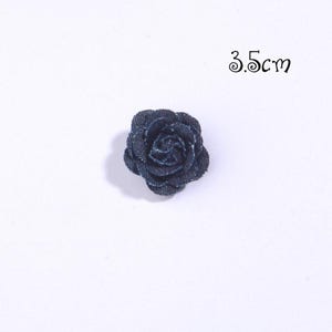 Puede incluir: Una rosa de tela vaquera azul oscuro, de aproximadamente 3,5 cm de di&aacute;metro, sobre un fondo blanco. La flor tiene m&uacute;ltiples capas de p&eacute;talos, creando una apariencia texturizada. Ideal para manualidades y adornos.
