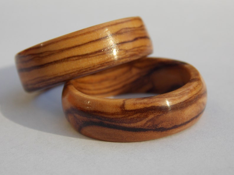 Puede incluir: Dos anillos de madera con un patr&oacute;n de veta de madera natural. Los anillos est&aacute;n apilados uno encima del otro.