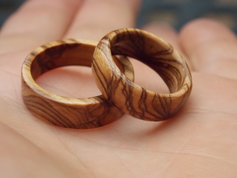 Puede incluir: Dos anillos de madera con un patr&oacute;n de veta de madera natural. Los anillos est&aacute;n hechos de madera marr&oacute;n claro con vetas marr&oacute;n oscuro.