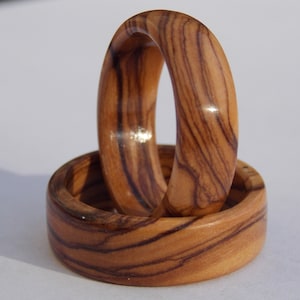 Puede incluir: Dos anillos de madera con un patr&oacute;n de veta de madera natural. Los anillos est&aacute;n apilados uno encima del otro.