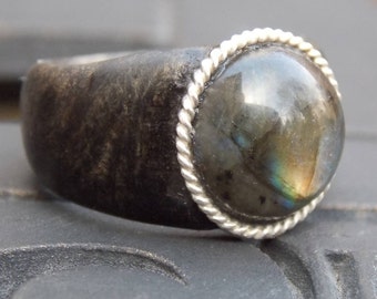 May include: A silver ring with a dark gray wooden band and a large iridescent labradorite gemstone set in a silver bezel.