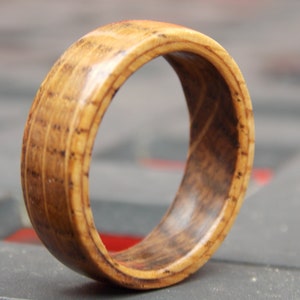 May include: A wooden ring with a natural brown finish. The ring has a wide band and a smooth, polished surface.