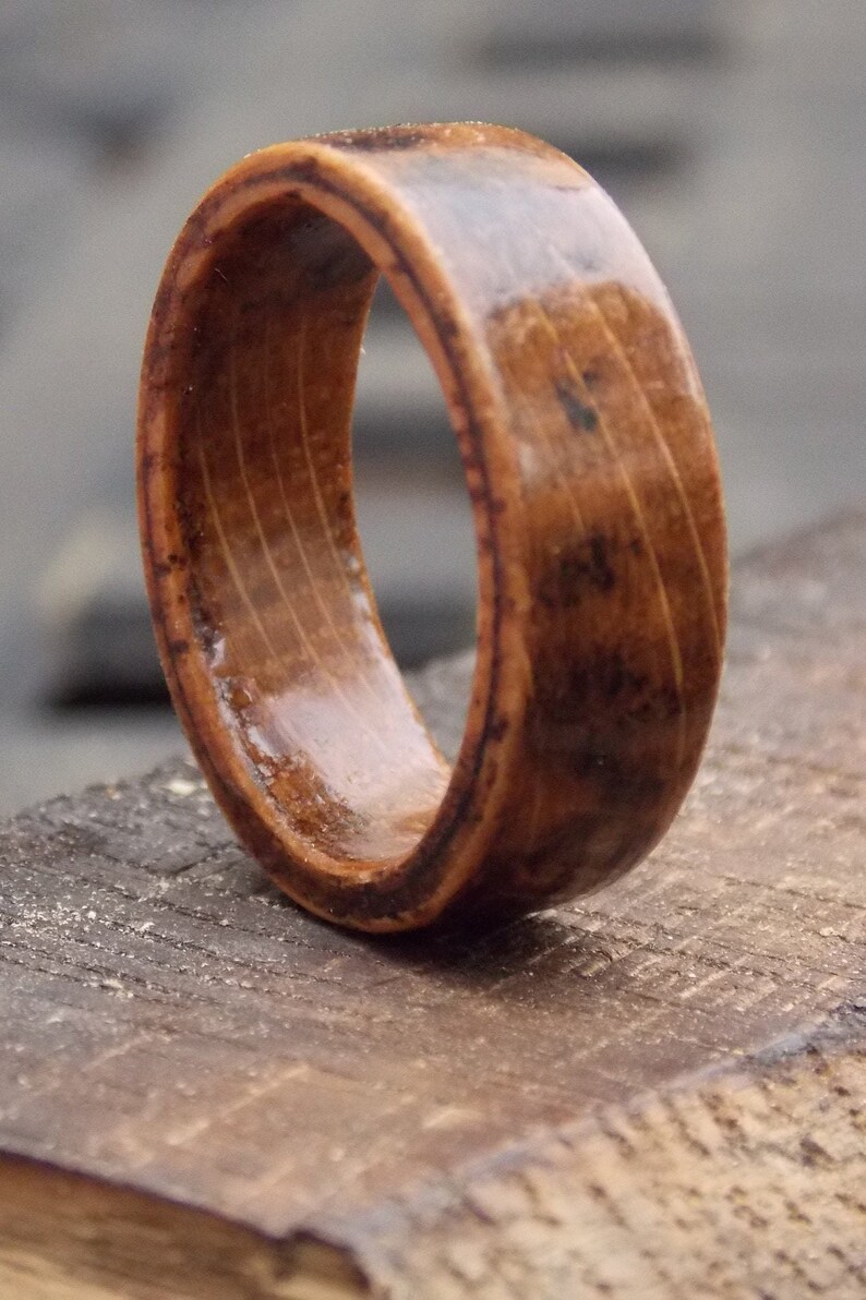 K&ouml;nnte beinhalten: Nahaufnahme eines Holzrings mit brauner und schwarzer Holzmaserung. Der Ring ist poliert und hat eine glatte Oberfl&auml;che.
