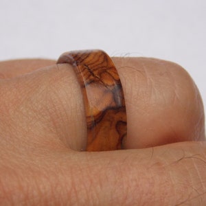 Puede incluir: Un anillo de madera con un patr&oacute;n de veta de madera marr&oacute;n y marr&oacute;n oscuro.